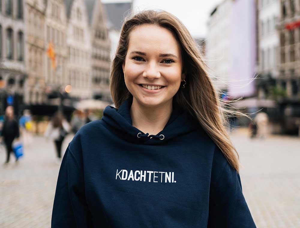 Vrouw met een donkerblauwe hoodie met opdruk KDACHTETNI.