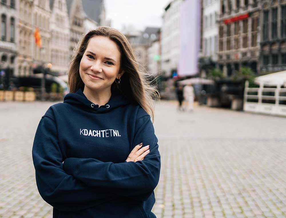 Vrouw met een donkerblauwe hoodie met opdruk KDACHTETNI.