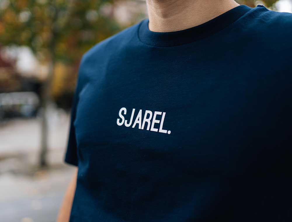 Man met een donkerblauwe T-shirt met opdruk SJAREL.