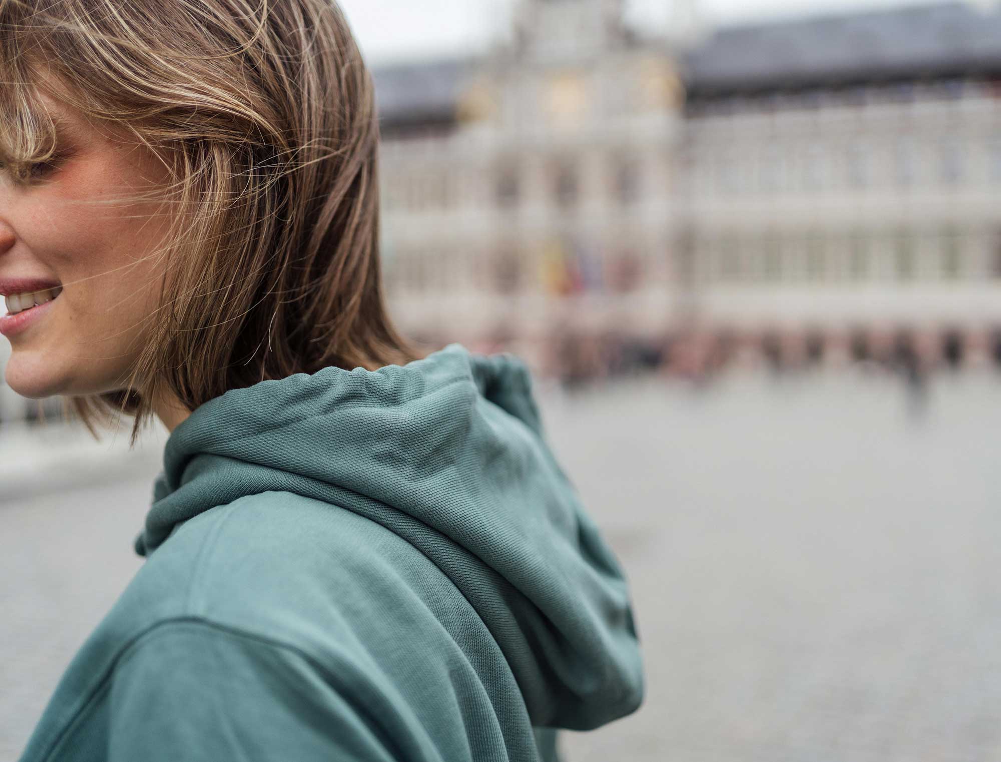 Vrouw met groene hoodie met opdruk DEVEURLESTE.