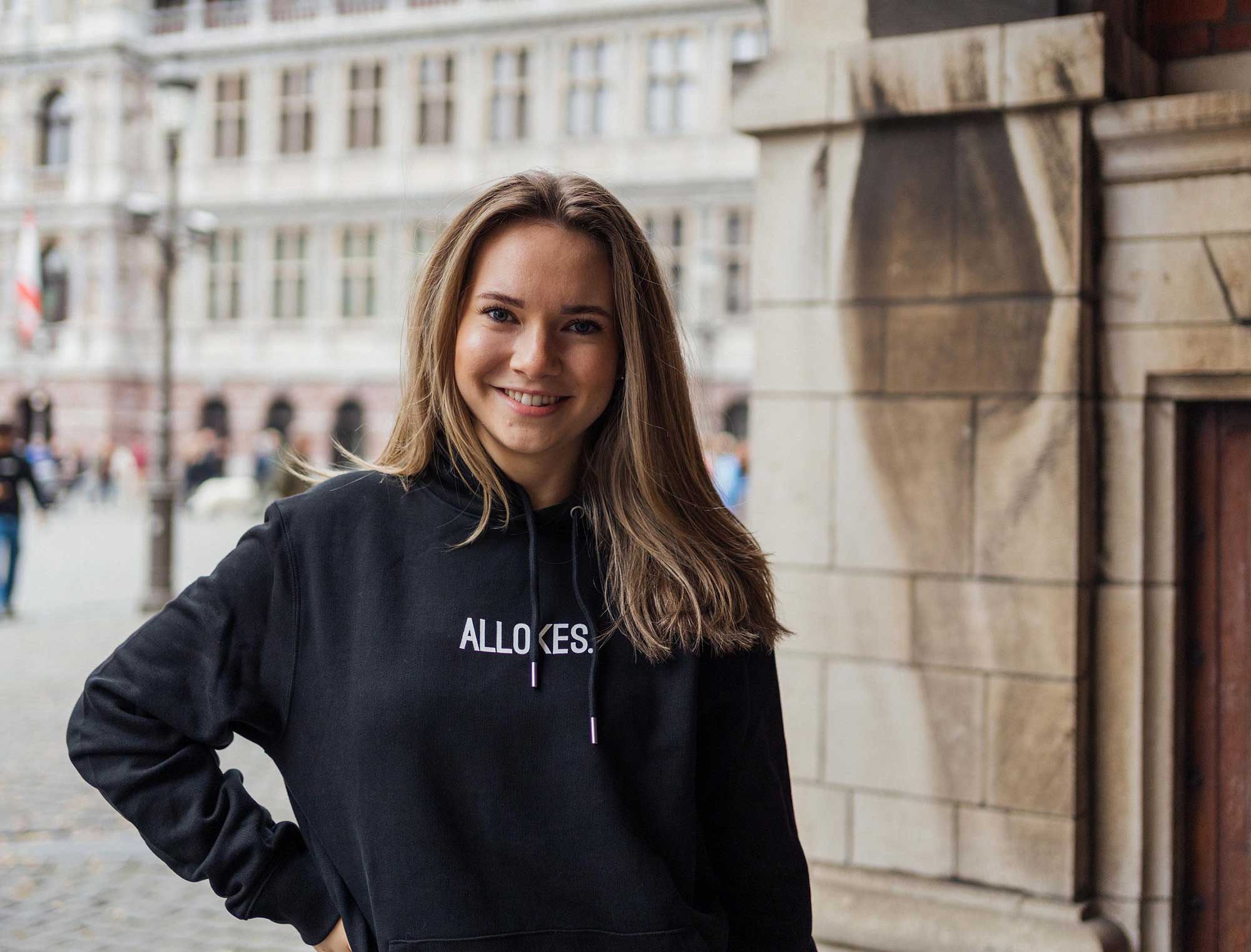 Vrouw met zwarte hoodie met opdruk ALLOKES.