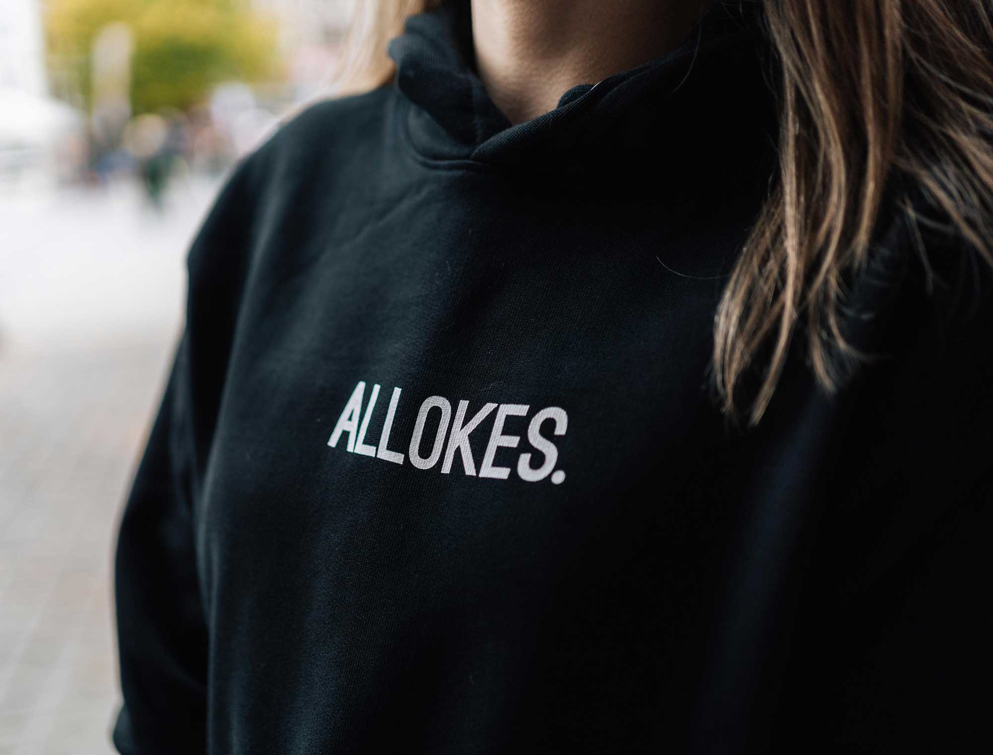 Vrouw met zwarte hoodie met opdruk ALLOKES.