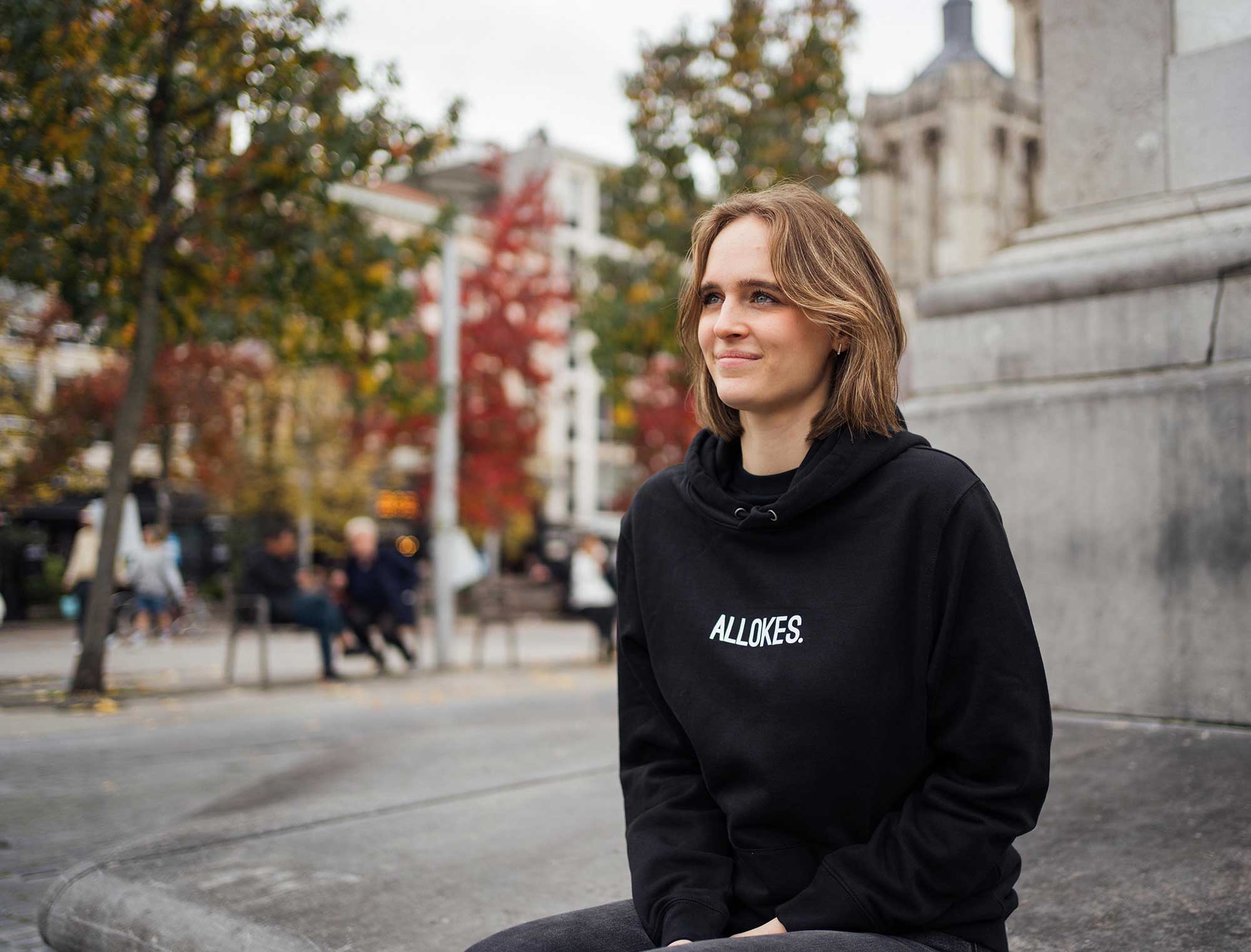 Vrouw met zwarte hoodie met opdruk ALLOKES.