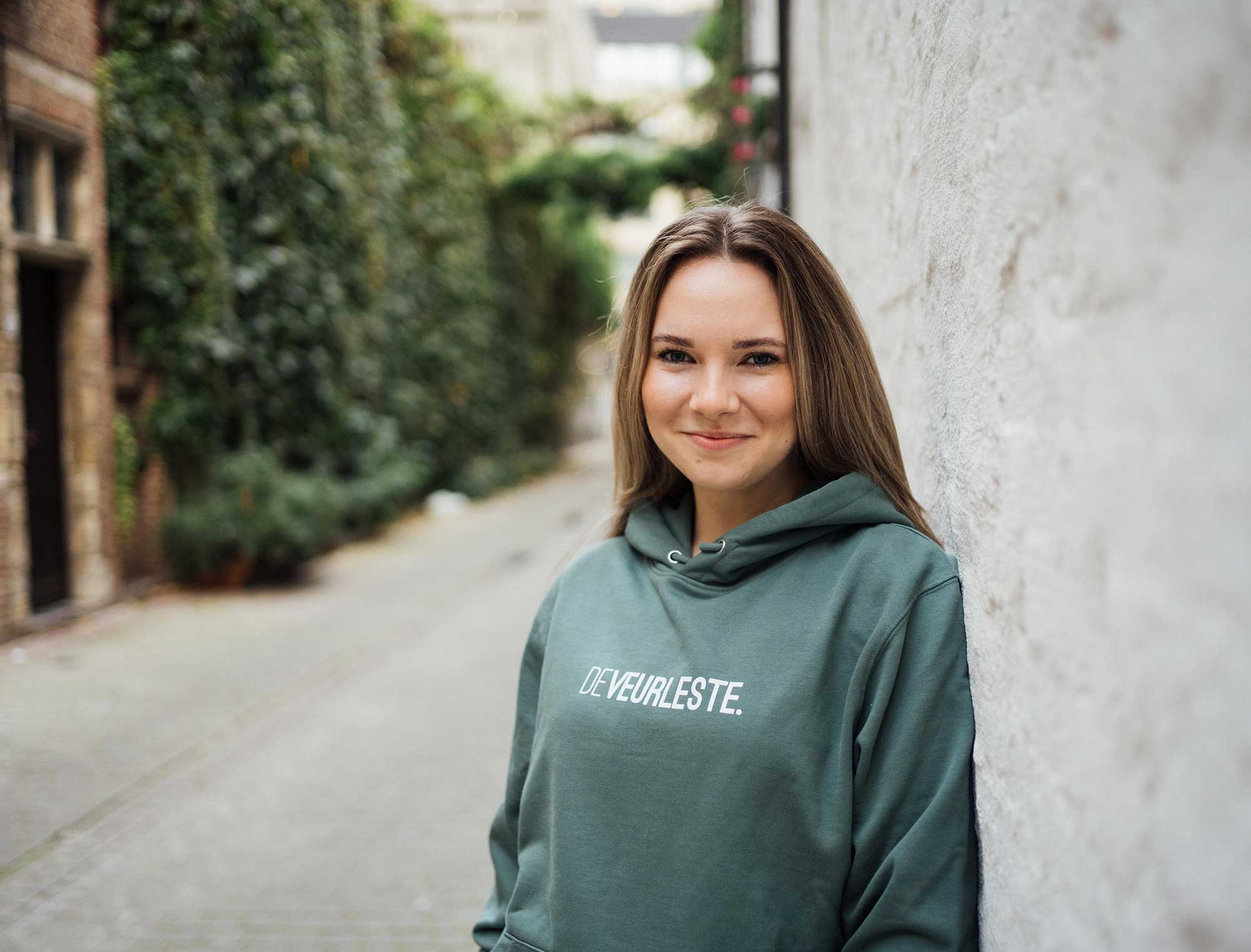 Vrouw met groene hoodie met opdruk DEVEURLESTE.