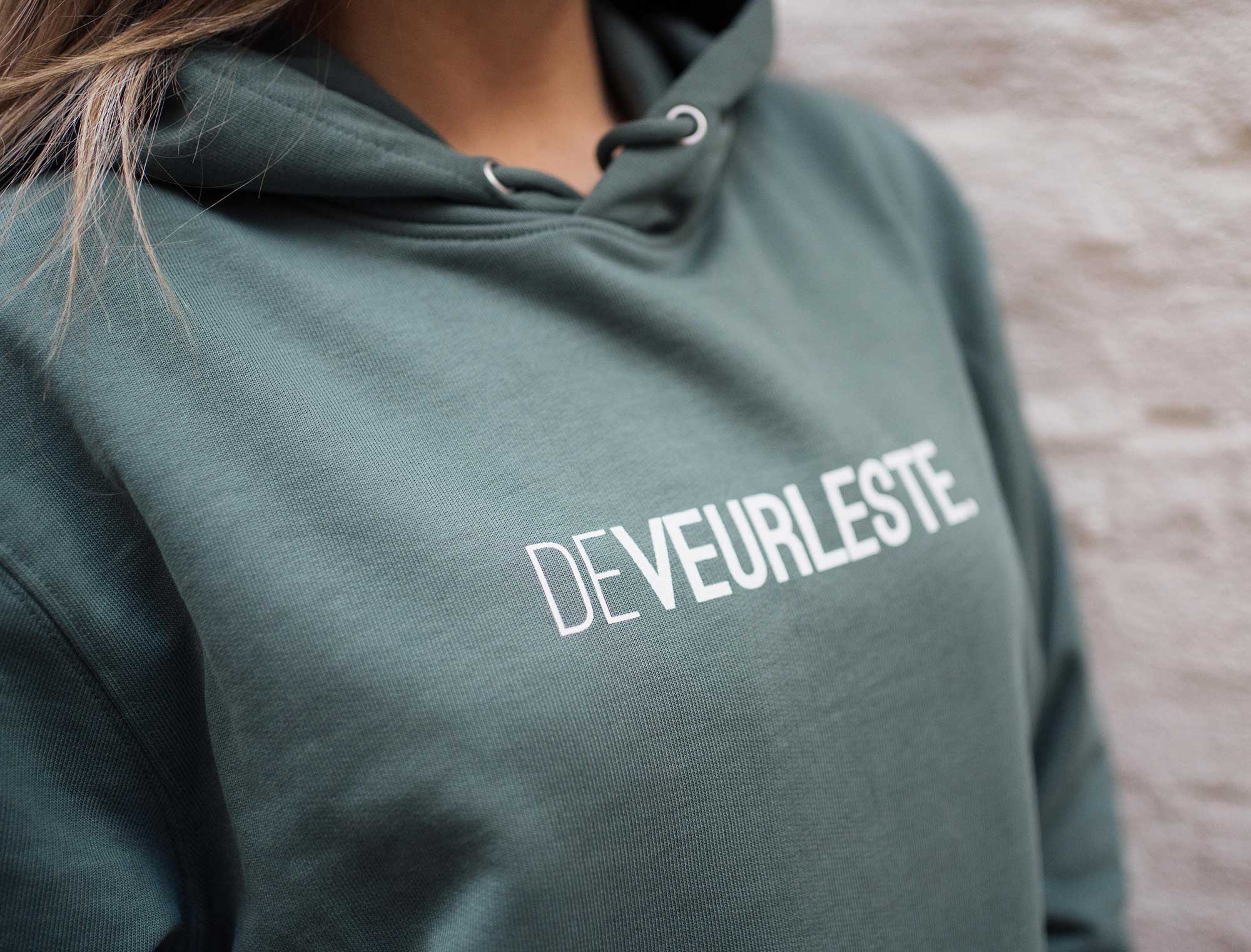 Vrouw met groene hoodie met opdruk DEVEURLESTE.