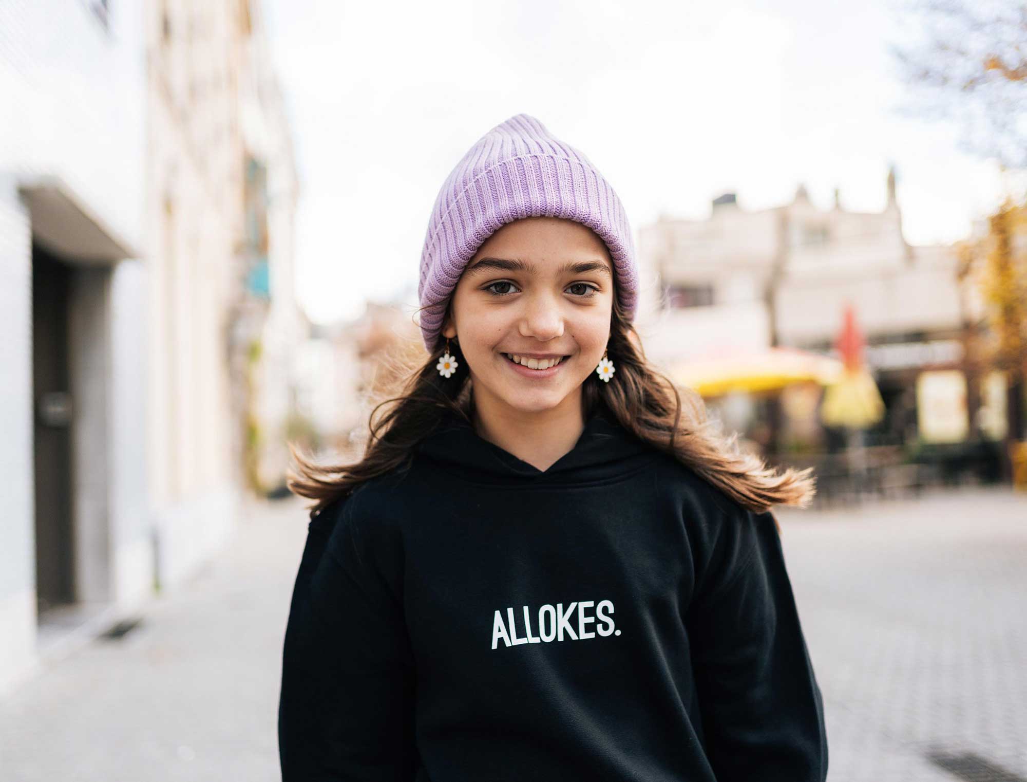 Meisje met een zwarte hoodie voor kinderen met opdruk 'ALLOKES.'