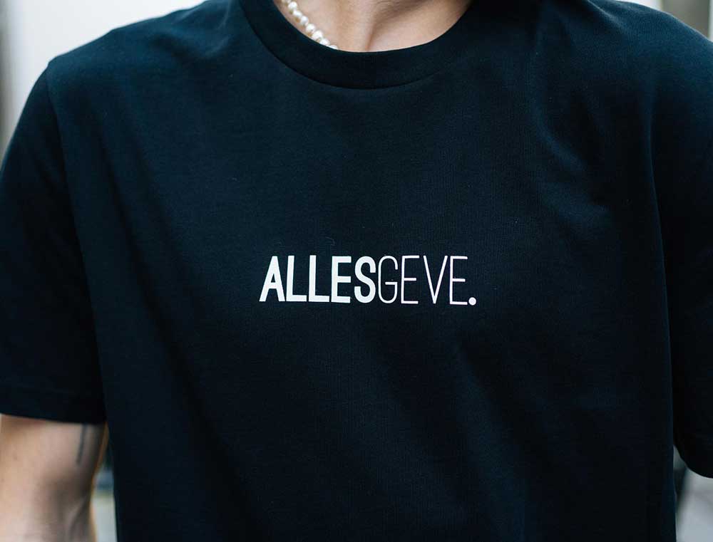 Close-up van een zwarte T-shirt met opdruk ALLESGEVE.