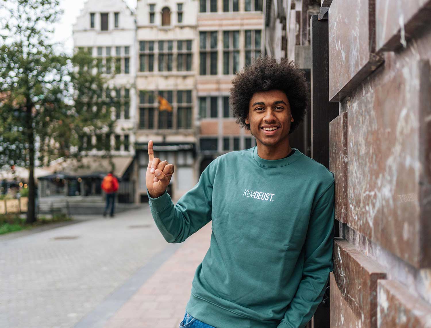 Man met een groene sweater met opdruk KEMDEUST.