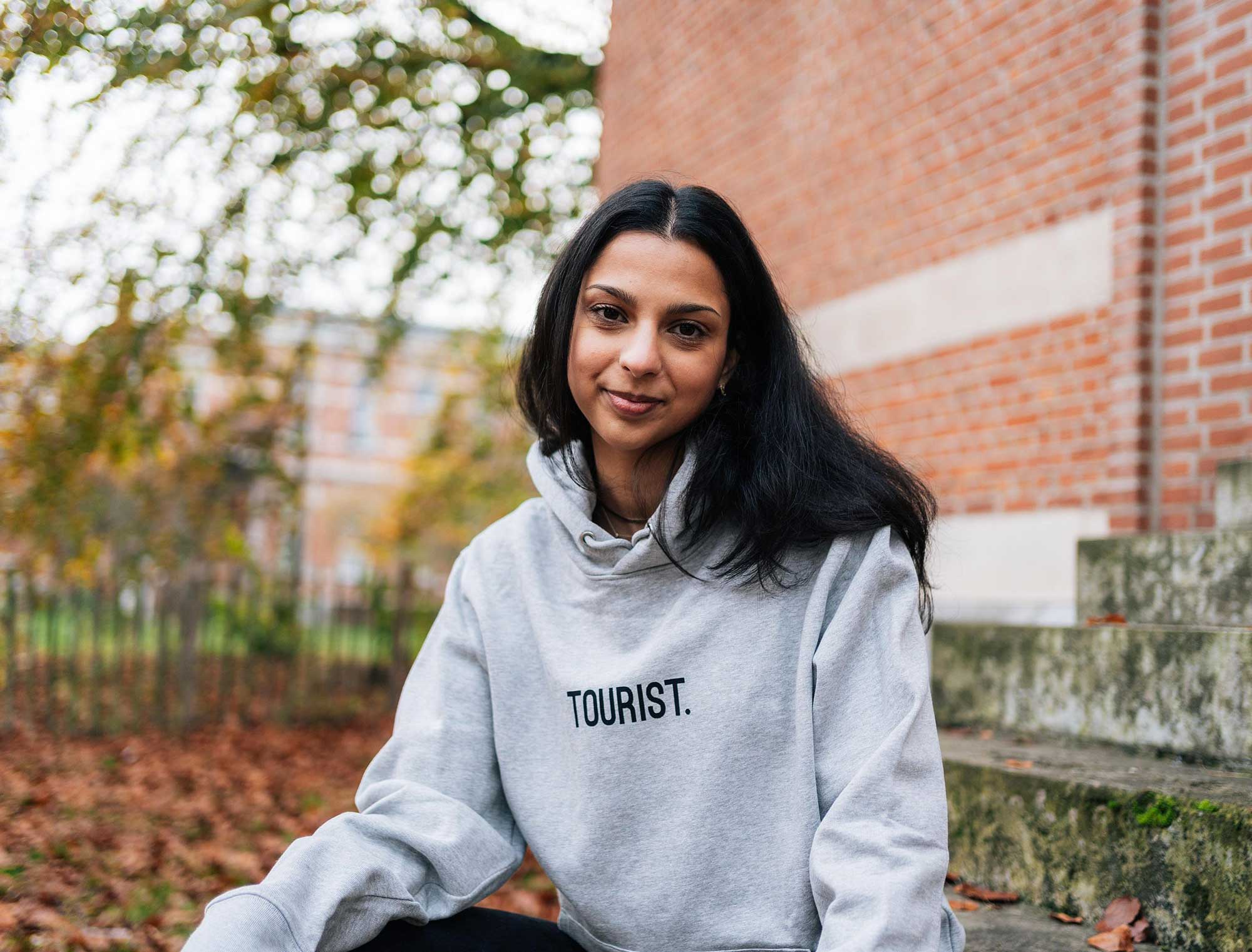 Vrouw met een grijze hoodie met opdruk TOURIST.