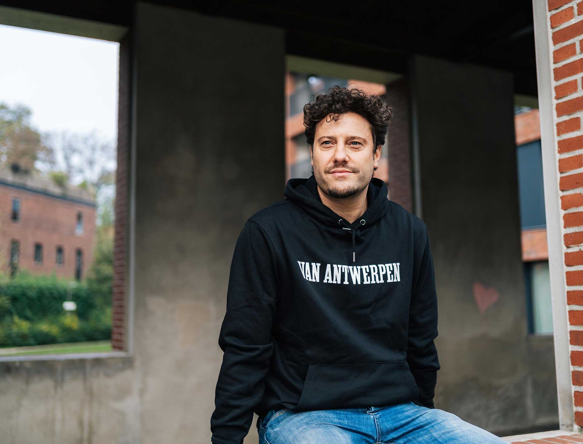 Man met een zwarte hoodie met opdruk Van Antwerpen in de typische GVA letters.