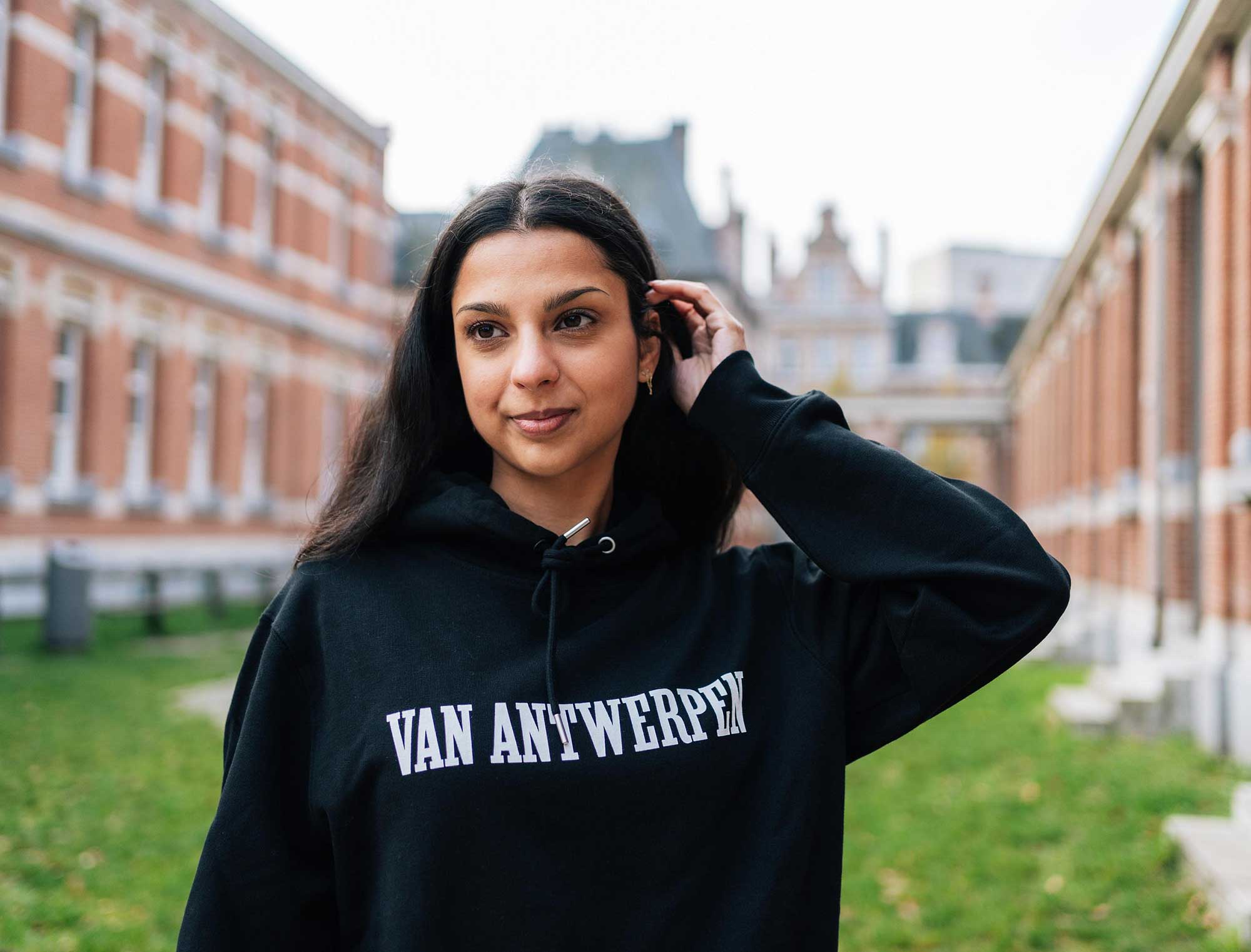 Vrouw met een zwarte hoodie met opdruk Van Antwerpen in de typische GVA letters.