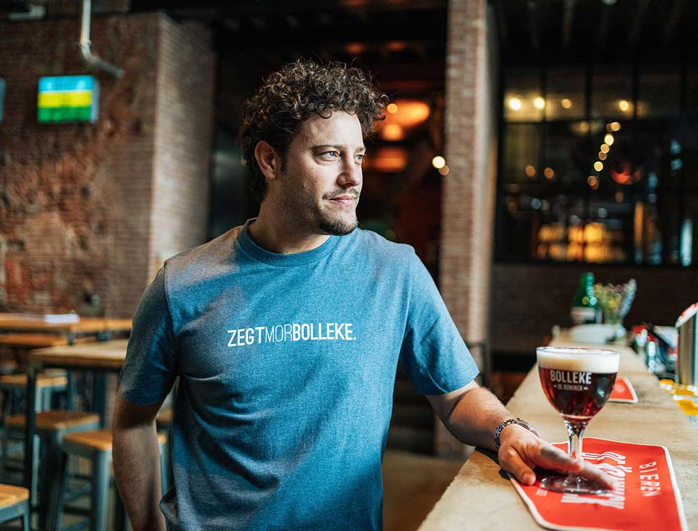 Man met een blauwe T-shirt met opdruk ZEGTMORBOLLEKE.